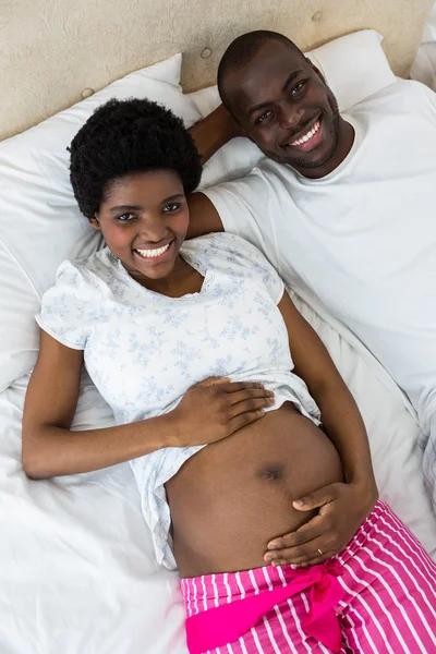 Pregnant couple relaxing on bed — Stock Photo, Image