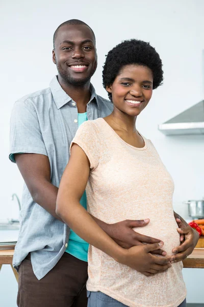 Беременная пара обнимается на кухне — стоковое фото