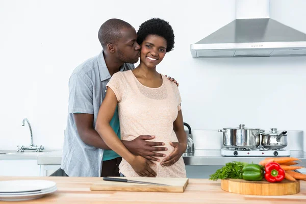 Έγκυος ζευγάρι αγκαλιάζει στην κουζίνα — Φωτογραφία Αρχείου