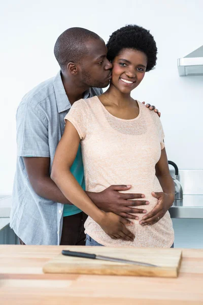 Casal grávida abraçando na cozinha — Fotografia de Stock