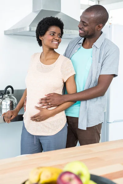 Casal grávida abraçando na cozinha — Fotografia de Stock