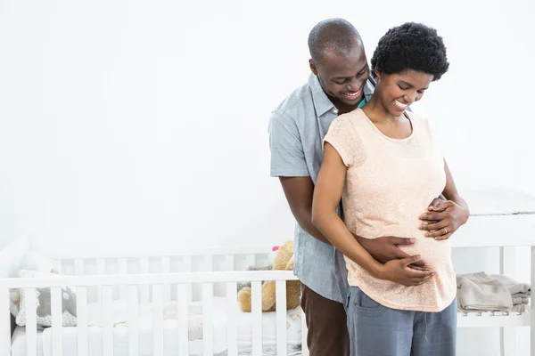 Pregnant couple embracing near cradle — Stock Photo, Image