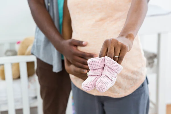 Embarazada pareja sosteniendo rosa bebé shoes — Foto de Stock