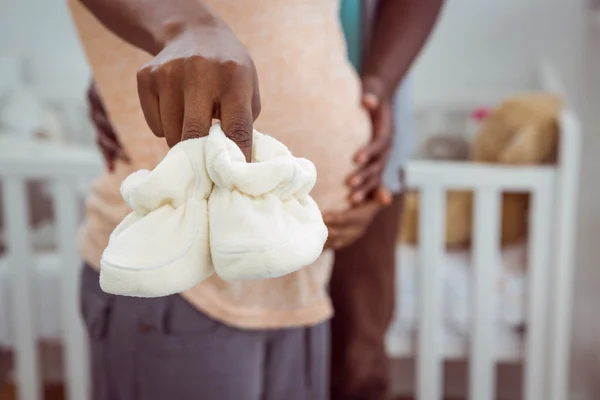 Pregnant couple holding white baby shoes — Stock Photo, Image