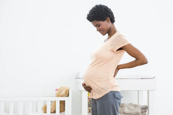 Беременная женщина стоит рядом с колыбелью — стоковое фото