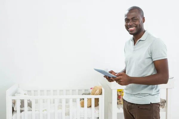 Smiling man standing next to a cradle — Stock Photo, Image