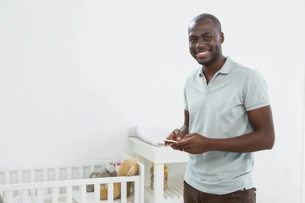 Smiling man standing next to a cradle — Stock Photo, Image