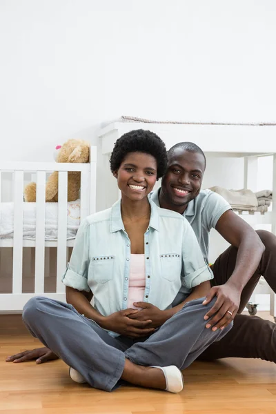 Pregnant couple sitting near baby cradle — Stock Photo, Image