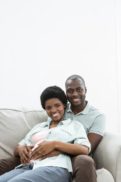 Man vidrör gravida kvinnans mage på soffan — Stockfoto