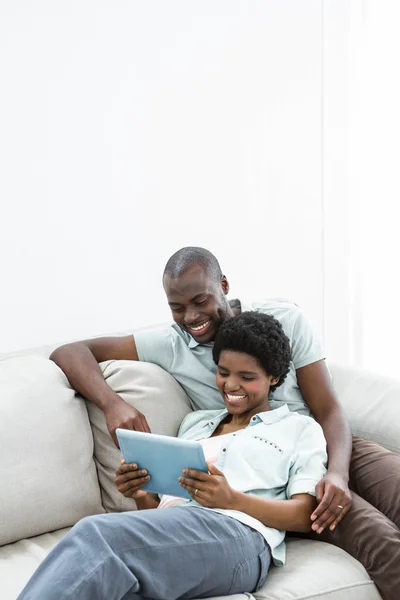 Έγκυος ζευγάρι χρησιμοποιώντας ψηφιακή δισκίο στον καναπέ — Φωτογραφία Αρχείου