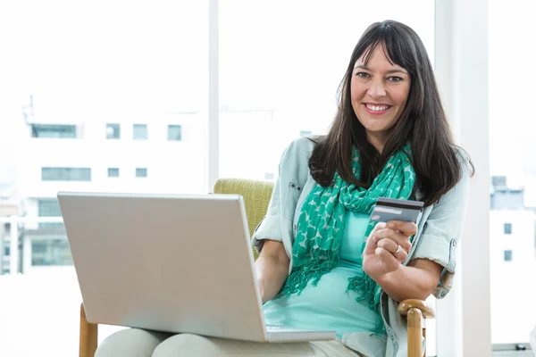 Feliz mujer embarazada de compras en línea en su computadora portátil — Foto de Stock