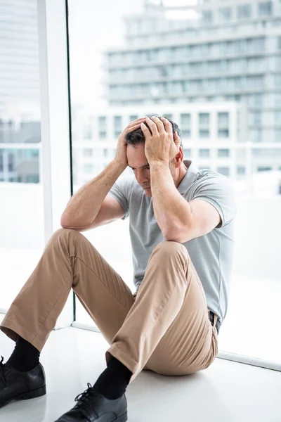 Tensed man sitting against window — Stock Photo, Image