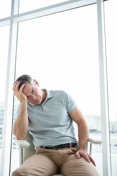 Verspannter Mann sitzt auf Stuhl gegen Fenster — Stockfoto