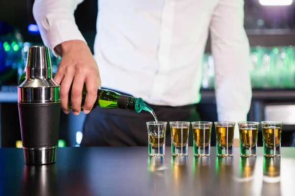 Bartender pouring tequila into shot glasses — Stock Photo, Image
