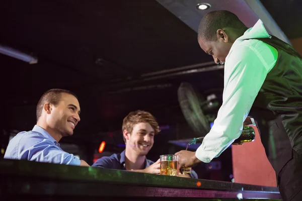 Bartendern serverar whisky till två män på bardisk — Stockfoto