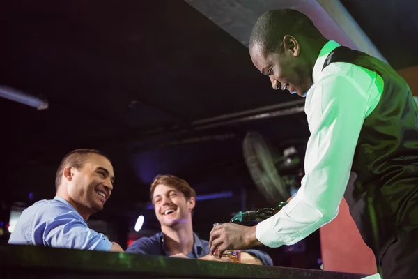 Cantinero sirviendo whisky a dos hombres en el mostrador del bar — Foto de Stock