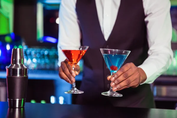 Cantinero sirviendo bebidas de cóctel azul y naranja — Foto de Stock