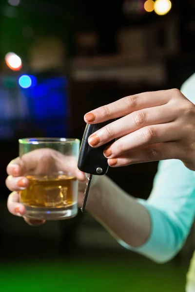 Mujer sosteniendo un vaso de whisky y llaves del coche — Foto de Stock