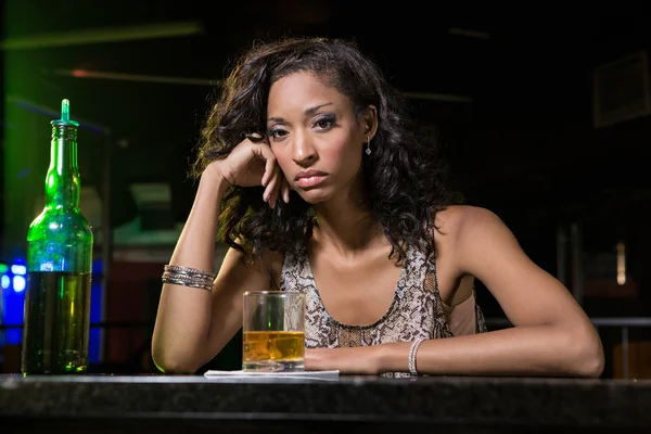 Депрессивная женщина пьет виски за барной стойкой — стоковое фото