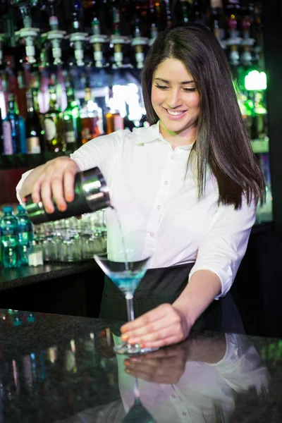 Grazioso barista che versa un drink di martini blu nel bicchiere — Foto Stock