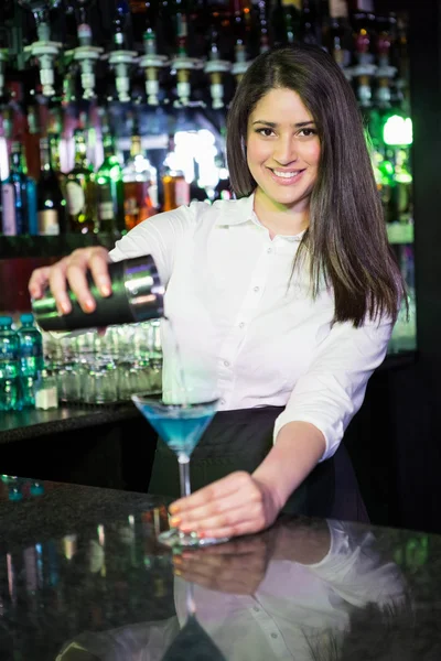Hübsche Barkeeperin gießt ein blaues Martini-Getränk ins Glas — Stockfoto