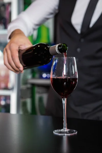 Partie médiane du barman versant du vin rouge dans un verre — Photo