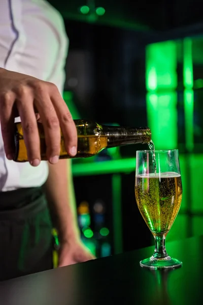 Sección media del camarero vertiendo cerveza en un vaso —  Fotos de Stock