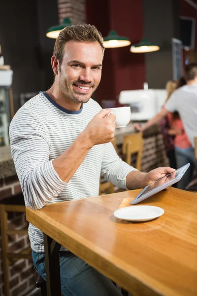 Человек с помощью планшетного компьютера и с кофе — стоковое фото