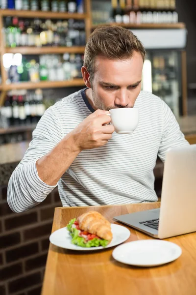 Uomo che utilizza il computer portatile e prendere un caffè — Foto Stock