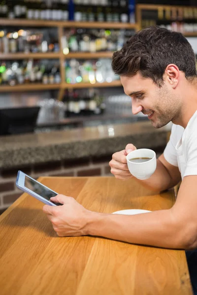 Bonito homem usando tablet e tomar café — Fotografia de Stock