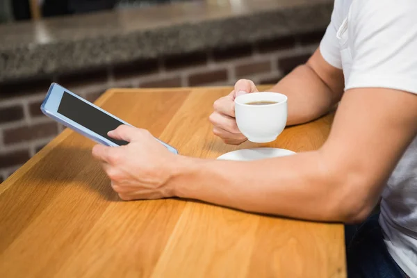 Knappe man met behulp van tablet en met koffie — Stockfoto