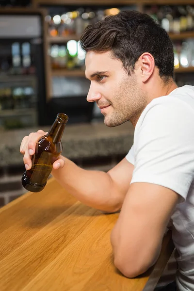 Un bel homme tenant une bouteille de bière — Photo