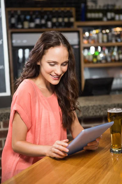 Mulher bonita tomando uma cerveja e olhando para tablet — Fotografia de Stock