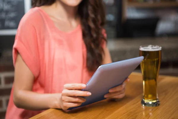 Mulher bonita tomando uma cerveja e olhando para tablet — Fotografia de Stock