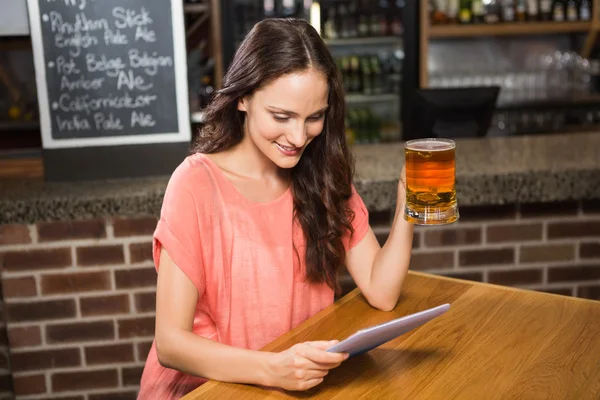 Hezká žena, na pivo a při pohledu na tabletu — Stock fotografie