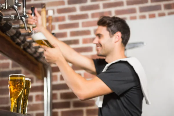 Handsome barman pouring a pint of beer — Stock Photo, Image