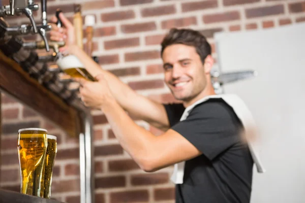 Knappe barman gieten van een pint bier — Stockfoto