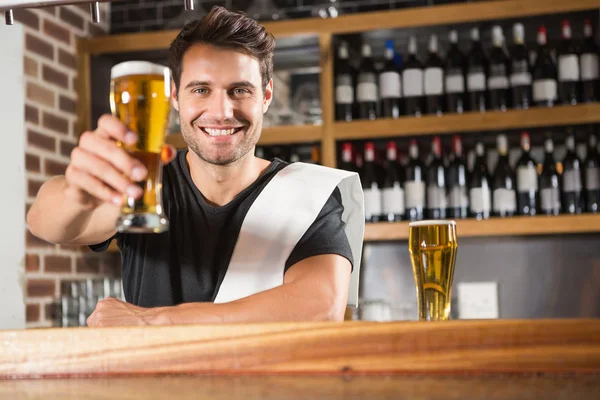 Bonito barman segurando uma caneca de cerveja — Fotografia de Stock