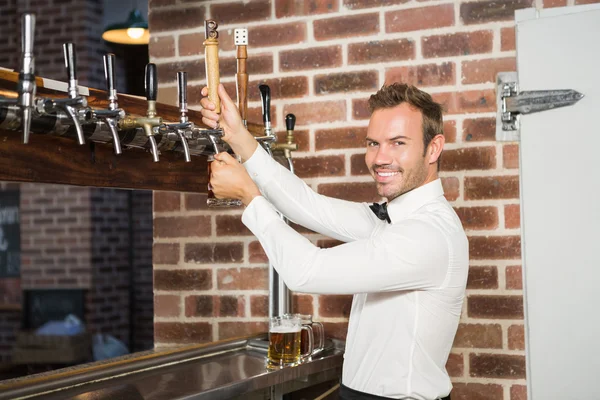 Guapo barman sirviendo una pinta de cerveza — Foto de Stock