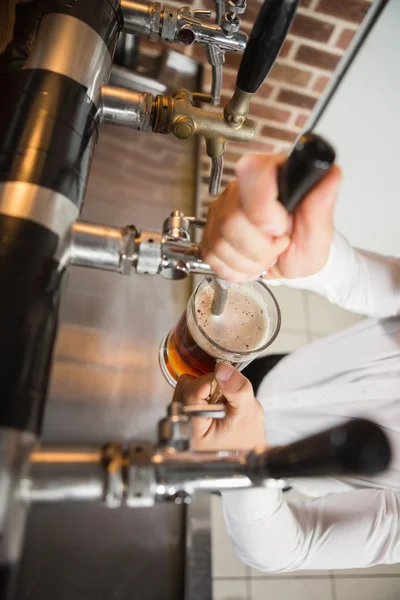 Schöner Barmann, der ein Pint Bier einschenkt — Stockfoto