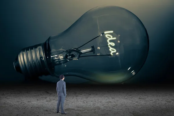 Businessman looking at giant light bulb — Stock Photo, Image