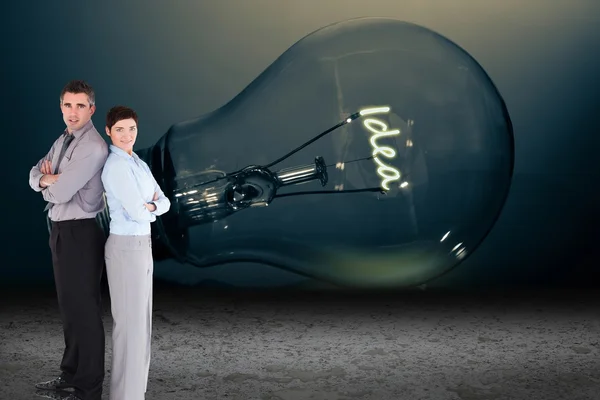 Business people standing in front of light bulb — Stock Photo, Image