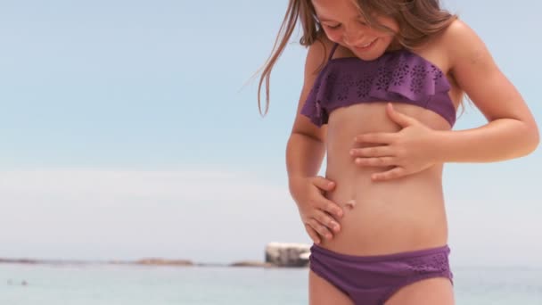 Lächelndes kleines Mädchen, das ihren Bauch berührt — Stockvideo