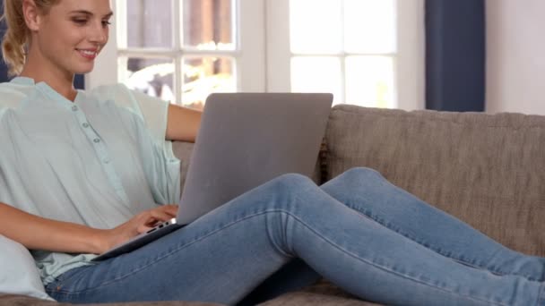 Carino bionda utilizzando il computer portatile sul divano — Video Stock