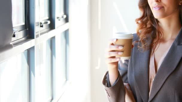 Geschäftsfrau trinkt Kaffee am Fenster — Stockvideo