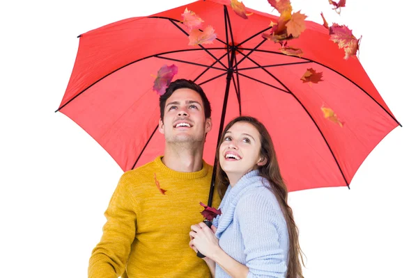 Casal feliz abaixo de um guarda-chuva jogando folhas — Fotografia de Stock