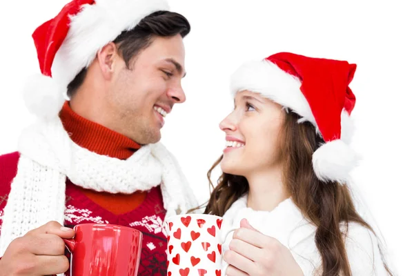 Casal com chapéus de Santa segurando canecas — Fotografia de Stock