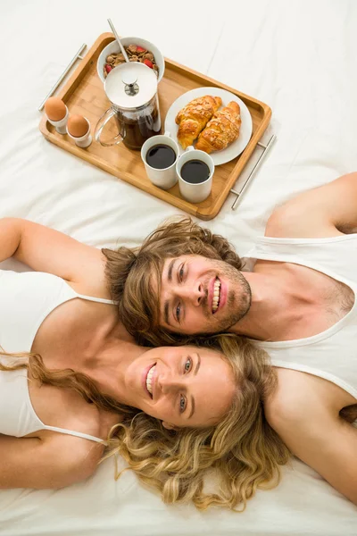 Nettes Paar liegt im Bett neben einem Frühstückstablett — Stockfoto