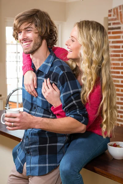 Couple cuddling with girlfriend sitting on the counter — Stock Photo, Image