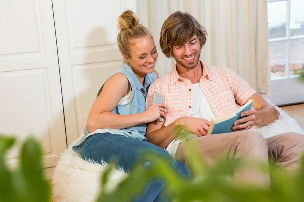 Paar liest ein Buch und nutzt Smartphone — Stockfoto